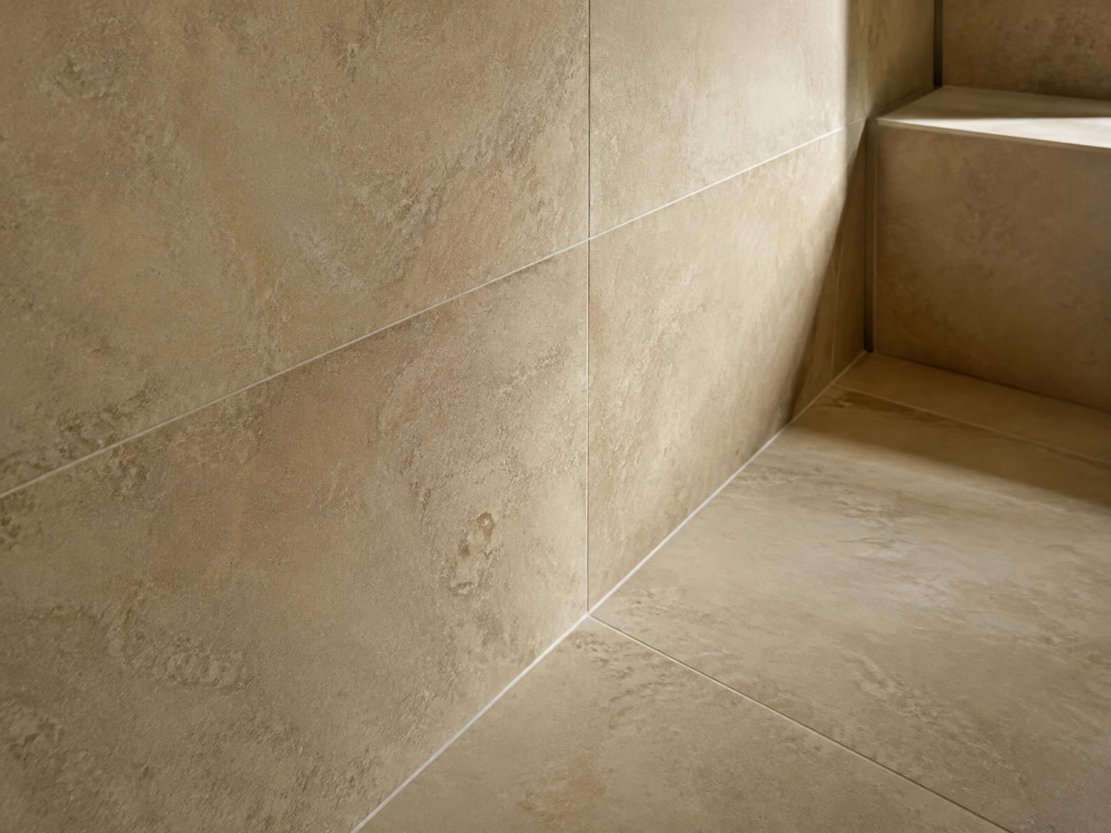 Detail großformatiger Fliesen in warmem Beige an Wand und Boden